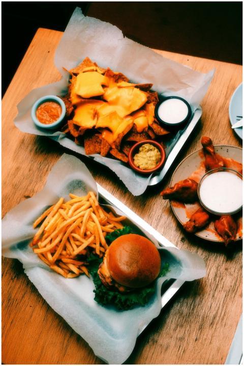 Tray of nachos, burger with fries, and buffalo win