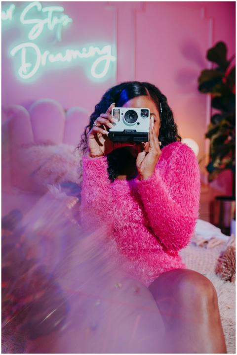 A fashionable woman holds a vintage camera in a co