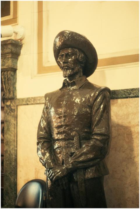 A bronze statue of a historic figure wearing a hat
