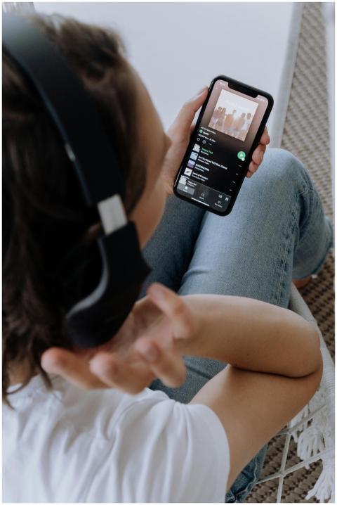 Person wearing headphones, using a smartphone to l