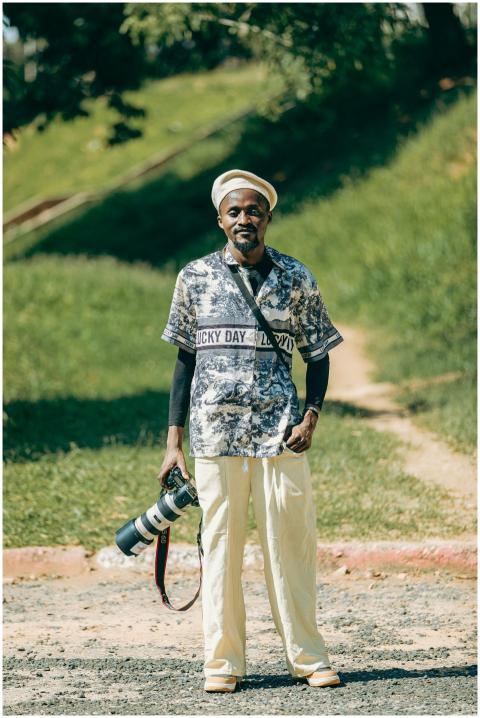 Man holding a professional camera outdoors, wearin
