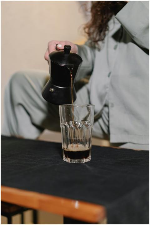 Person in pajamas pouring coffee from a moka pot i