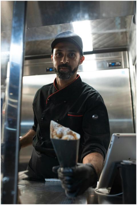 A chef dressed in black presenting a shawarma in a