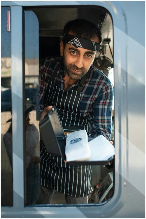 Smiling food truck vendor serving delicious shawar