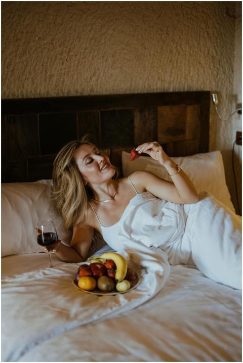 Woman enjoys fruit and wine in a cozy hotel room,