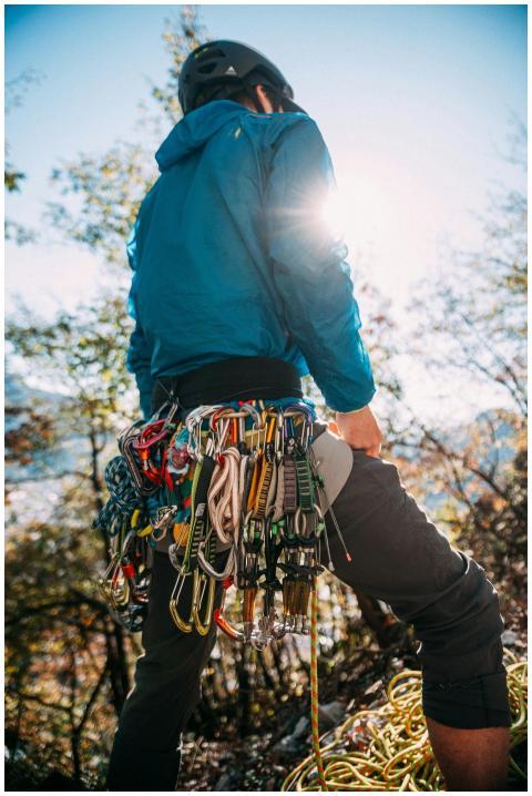 A mountain climber stands equipped with gear, faci