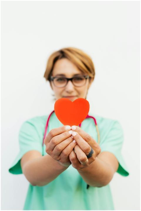 Focused healthcare worker holding a red heart, sym