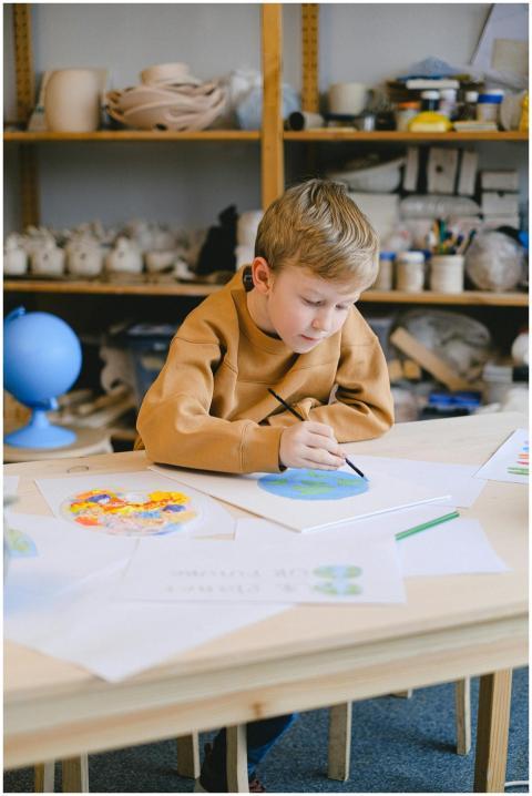 A young boy focused on a painting project in a cla