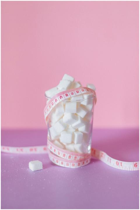 A glass of sugar cubes wrapped in measuring tape o