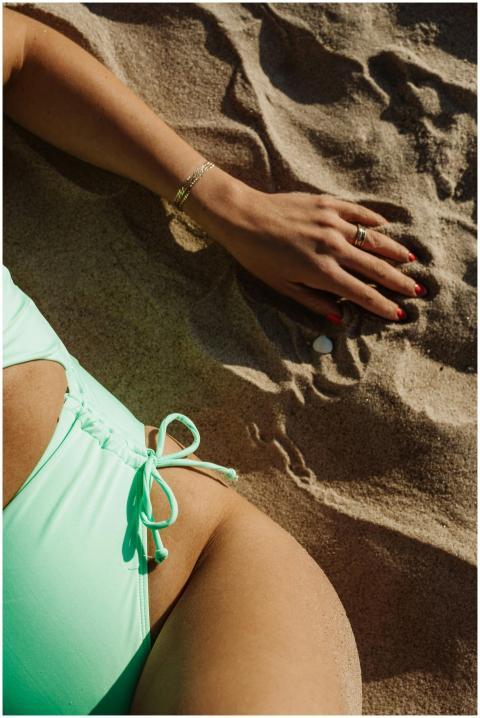 A woman's hand with painted nails rests on sand ne