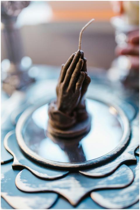 Handcrafted candle shaped like praying hands on a