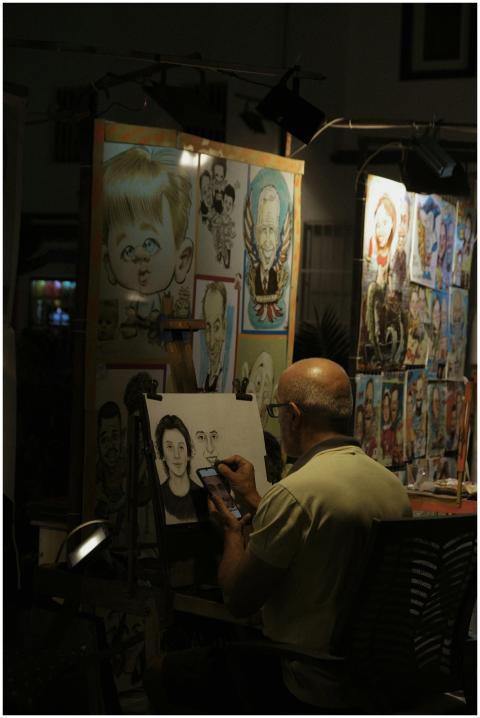 An artist sketches a portrait in a dimly lit art s