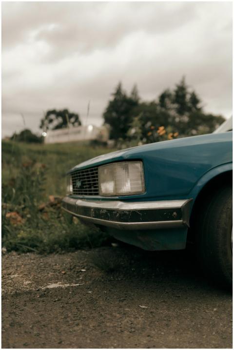 Close-up of a blue vintage car parked on a rural r