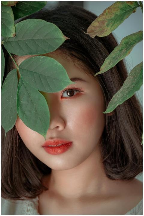 Close-up portrait of a woman peeking through green