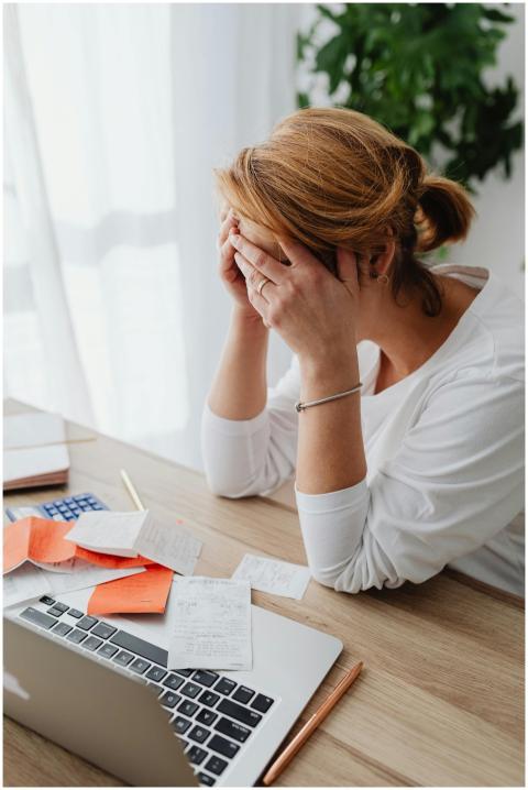 Overwhelmed woman sitting at desk with laptop and