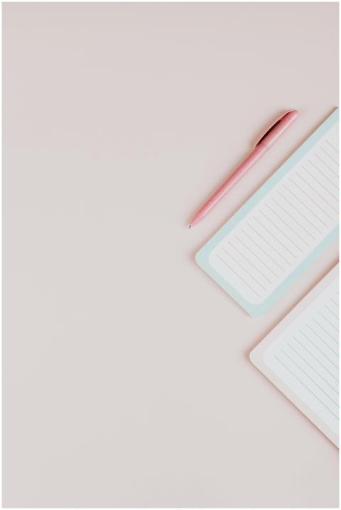 Pink pen and lined notepad on a pastel surface, pe