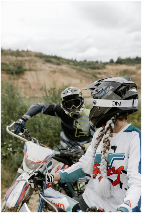 Two motocross riders with helmets ready for an out