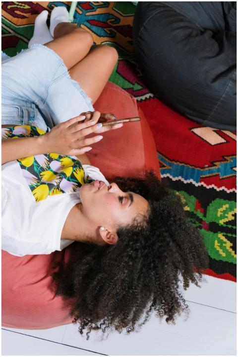 Young woman with curly hair using smartphone, rela