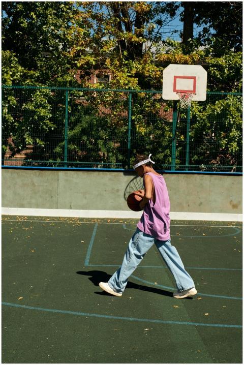 Young person dribbling basketball on an outdoor co
