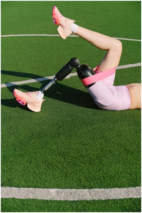 An athlete with a prosthetic leg stretching on a f