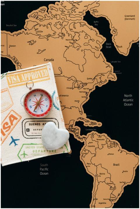 Flat lay photo of a map, passport, and compass, sy