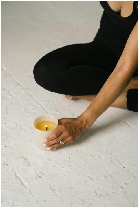 A woman in yoga pose holding a lit candle, embraci