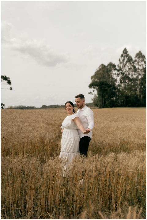 Couple standing in a wheat field, embracing under