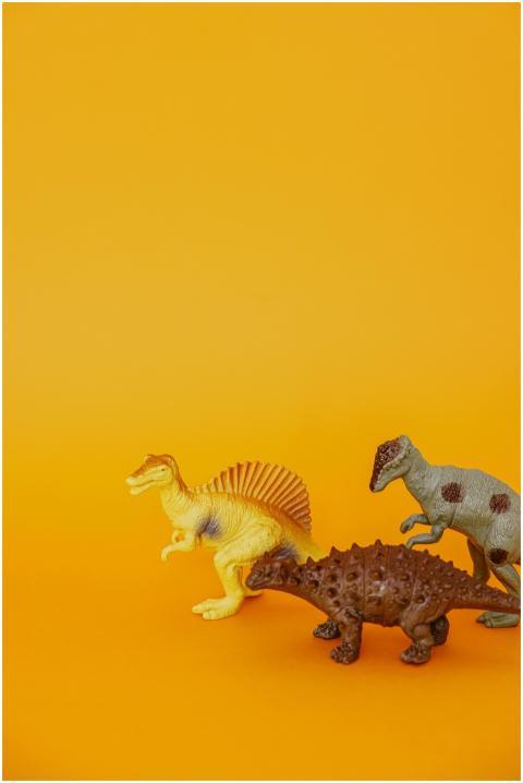 A trio of realistic dinosaur toys set against a br