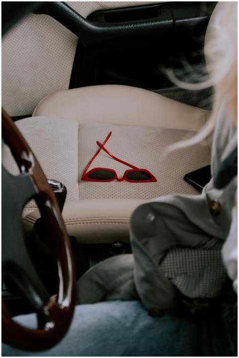 Close-up of stylish red sunglasses on a car seat,