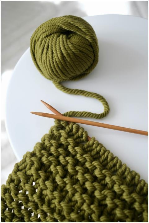 Green yarn and knitting needles on a table, showca