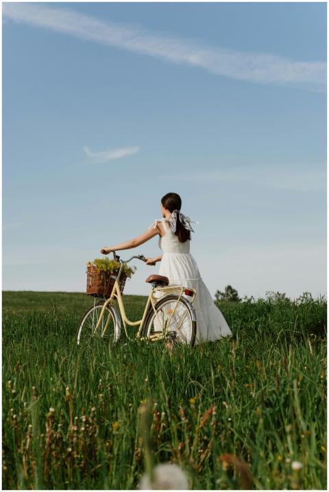 A woman in a white dress stands in a meadow with a