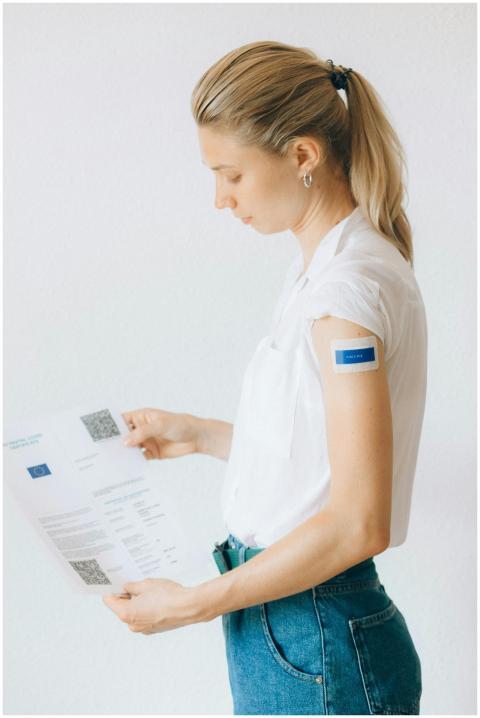 A woman reads her vaccination certificate with a v
