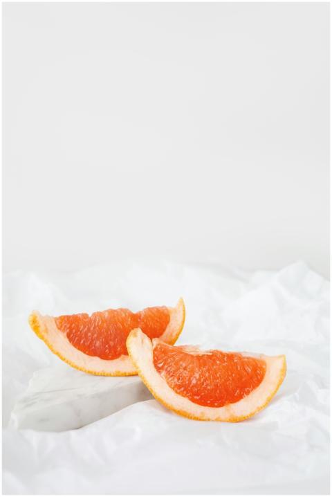 Two juicy grapefruit slices on a crisp white backg