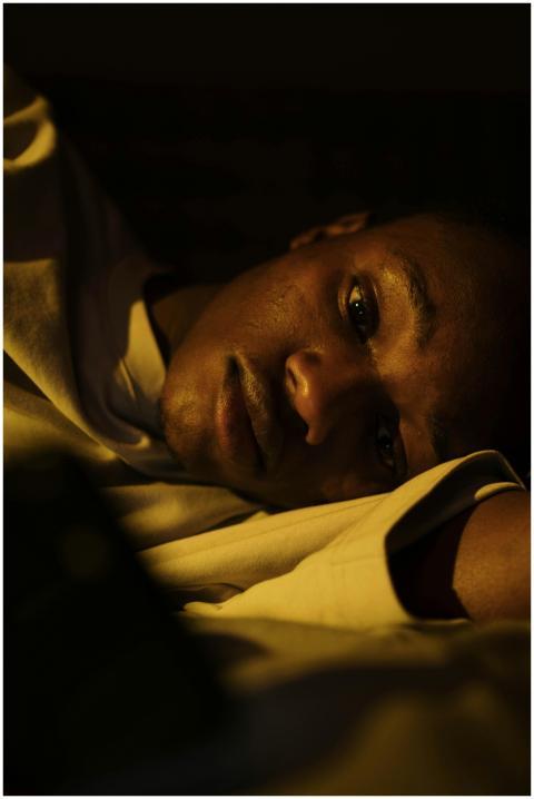 A young man lying awake in bed, depicting insomnia