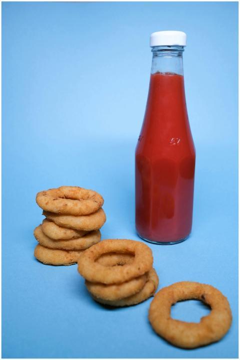 Tasty golden deep fried onion rings near bottle wi