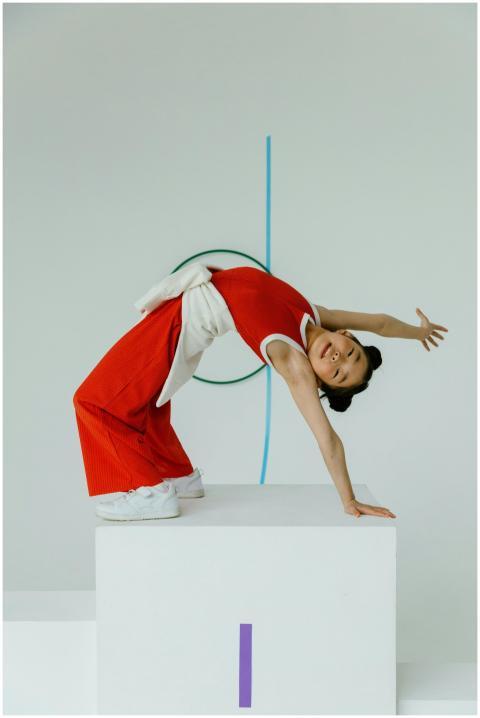 Child gymnast in red outfit performing a flexible