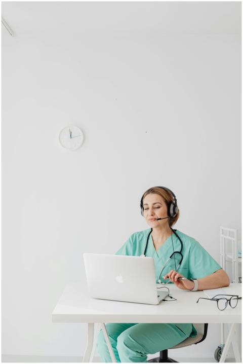 Female doctor in scrubs using laptop for virtual c