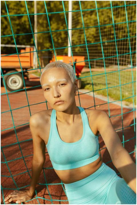 Confident woman in sportswear sitting by a net on