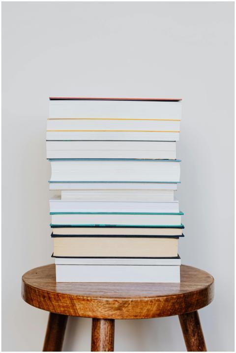 A neat stack of books placed on a rustic wooden st