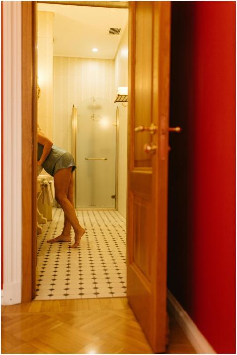 A woman stands at a bathroom sink in sleepwear, fr