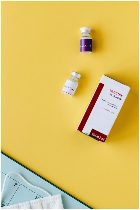 Top view of COVID-19 vaccine vials and box on a ye