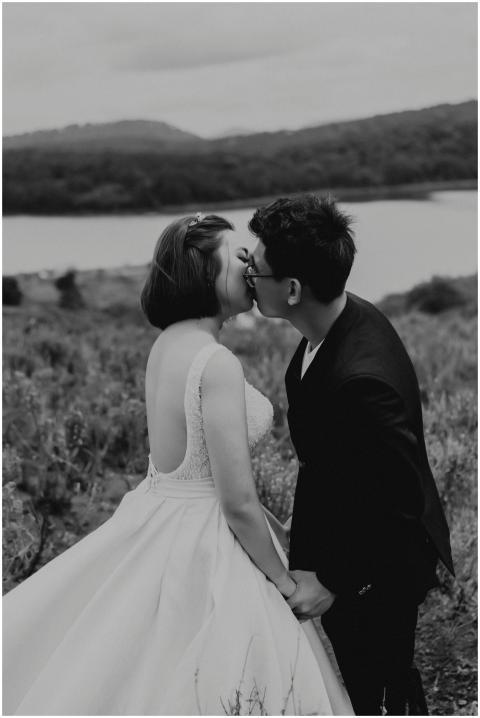 A bride and groom share a romantic kiss outdoors i