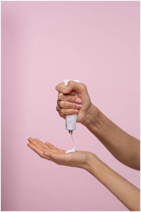 Close-up of a person applying cream from a tube ag