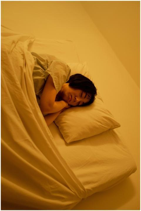 An adult woman sleeps peacefully under a blanket i