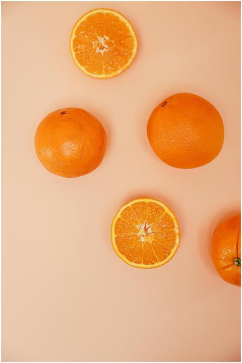 Fresh oranges on a peach background, showcasing ju