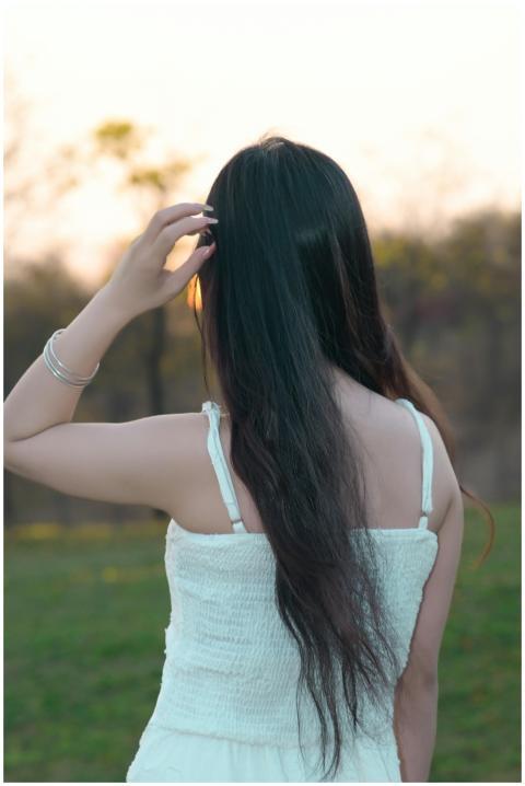 Woman with long dark hair in a white dress enjoyin