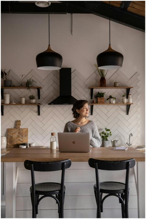Cheerful female in gray sweater sitting at wooden