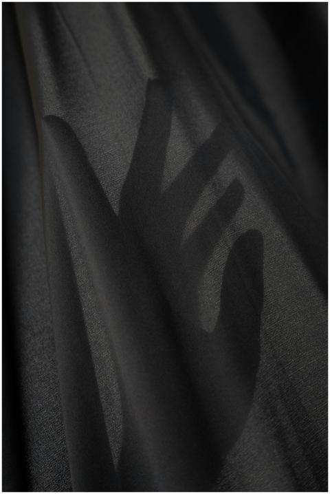 Artistic photo of a hand shadow cast on a black fa