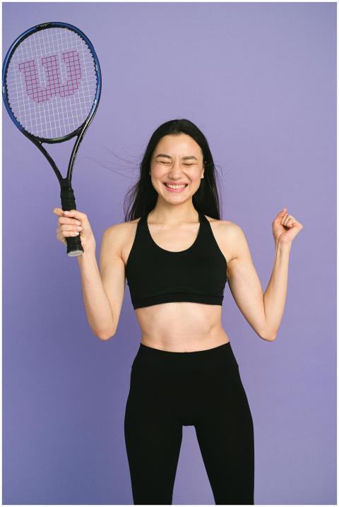 Smiling woman in sportswear holding a tennis racke