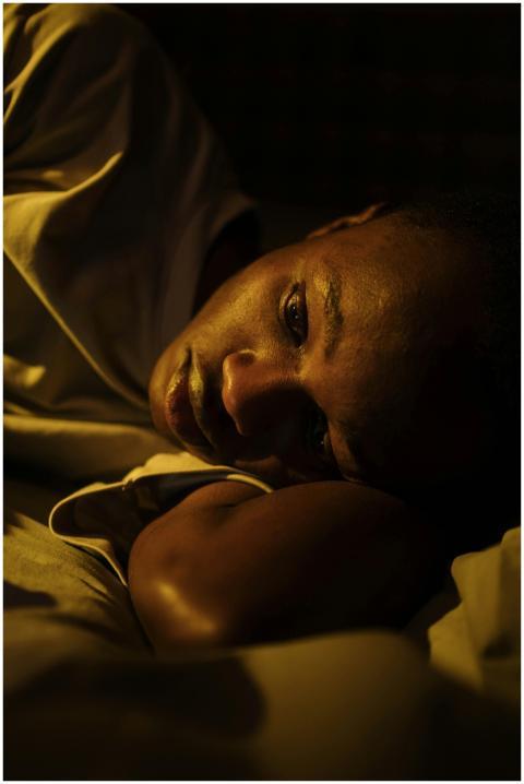 A young man lying awake in bed, reflecting insomni